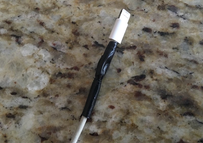 用电工胶带临时固定的修复破损的 iPhone 充电器